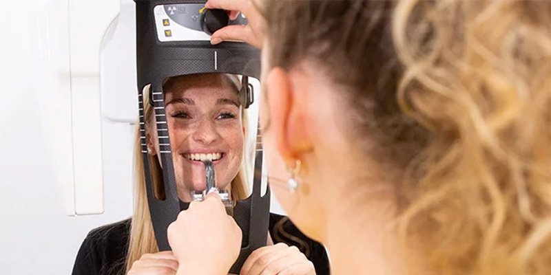 Assistentin stellt Röntgengerät für eine Patientin ein